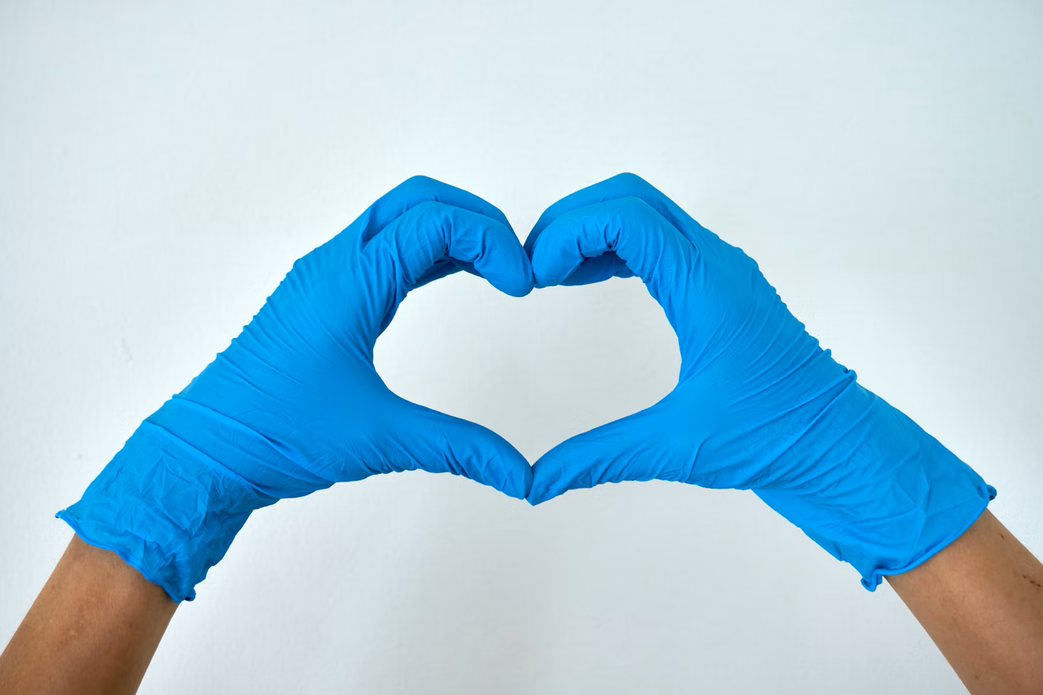 nurse holding up a heart with blue gloves on