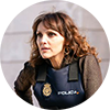 Ines Villegoes has brown long hair, is wearing a brown long sleeve shirt and is wearing a police cover over it