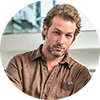 Max Winter has brown short hair, a beard, and has a brown shirt on
